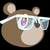 Brown bear head with light brown ears and muzzle, wearing white-framed glasses reflecting pink and yellow shapes on black background.
