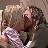 Pixelated image of two figures in close physical contact, one with light-colored hair and the other with dark curly hair, against a muted background.