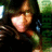 Pixelated image of a figure with light skin tones holding a glowing pinkish object against a dark background with green and blue elements.