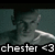 Pixelated image of a person with dark hair and light skin, wearing a white shirt against a teal background, with text 'chester <3' at the bottom.