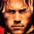 Pixelated close-up of a person's face with light brown hair and warm-toned skin, rendered in low-resolution JPEG format on a dark background.