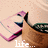 Pixelated image of a character with pink hair and a white face, wearing a dark blue outfit with a green shoulder piece, holding a pink object, with partial text 'life' visible at the bottom.
