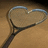 A tennis racket forms a heart shape on the left, with pixelated text 'tennis', 'love', and '<33' on a bright pink background.