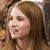 A pixelated close-up of a person with light brown hair, closed eyes, and a slight smile, wearing a light-colored top against a blurred background.