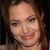 Pixelated close-up of a person with light skin tone, brown hair, and a smiling expression against a dark background.
