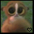 Pixelated close-up of a small primate-like creature with large dark eyes and light brown fur against a green background, featuring a black pixel-art heart symbol in the bottom-right corner.