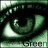 A pixelated close-up of a green-toned eye with visible eyelashes and a light reflection, featuring partial text at the bottom.