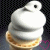 A white soft-serve ice cream cone with a waffle base, pink heart symbols in the background.