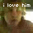 Pixelated image with white text 'i love him' overlaid on a blurred figure in a dimly lit environment with green and brown tones.