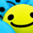 Yellow smiley face with black eyes and mouth on blue background, surrounded by pixelated text in light blue.