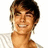 Pixelated image of a smiling person with short brown hair wearing a white striped shirt, set against a bright pink background with blue text.