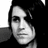 Pixelated grayscale portrait of a person with dark hair and a neutral expression, cropped to show shoulders and head against a dark background.