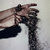 Pixelated image of a figure in dark clothing holding a long object against a light background.