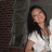 A static image shows a person with long dark hair wearing a white sleeveless top against a blurred background.