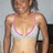 Pixelated image of a person wearing a white top with pink trim, standing against a light background.