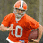 Pixelated image of a football player in an orange jersey holding a football, with text on a red background.