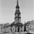 Black-and-white pixelated image of a tall, narrow tower with a spire, set against a light background with indistinct lower structures.