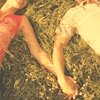 Two people lying on grass, one in red shorts, the other in light-colored shorts, with visible legs and feet.
