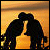 Two dark silhouetted figures embrace against a gradient background of orange and yellow hues.