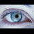 A close-up of a human eye with a light blue iris, dark pupil, and visible eyelashes, set against a pale background.