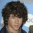 A person with curly brown hair and a dark jacket appears in three showing slight head movement against a light blue background
