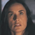 Pixelated close-up of a person with dark hair and light skin, showing facial features against a muted background.