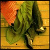 A static image shows a person's lower body in green pants and patterned shoes on a wooden floor, with a red fabric partially visible.