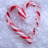 Two candy cane arrangements form heart shapes on a light blue background, with one heart displaying green text.
