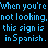 Pixelated blue text on black background repeats phrases about a sign being in Spanish, with one instance of the phrase fading to gray.