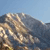 Pixelated static image showing a mountainous landscape with blue sky background and indistinct terrain features.