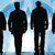 Silhouetted figures stand against a pixelated blue and white background with visible horizontal banding.