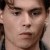 Pixelated close-up of a person's face with dark hair, neutral expression, and visible eyes, nose, and mouth against a light background.