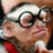 Pixelated close-up of a person wearing dark-rimmed glasses and a red garment, with a light-colored background.