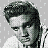 Pixelated grayscale image of a person with styled hair and white clothing next to bold black text reading "Elvis has left the building" on a light gray background.