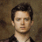 A pixelated image of a person with dark hair and light skin wearing a black shirt against a brown background, next to green text reading 'OriginalIcons.com' on a solid green backdrop.