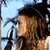 Pixelated static image of a person with curly hair in profile view against a light blue background, featuring visible dithering and color blending artifacts typical of low-resolution digital art.