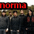 Group of people in dark clothing standing outdoors with trees and sky background, text overlays change between frames.