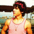 A person in a pink tank top and red headband stands against an outdoor backdrop with water and buildings, showing slight variations