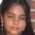 Pixelated close-up of a person with dark hair and light skin, showing facial features and earrings against a blurred background.