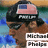 Pixelated image of a person wearing dark sunglasses, a black cap with an American flag design, and brown clothing against a blue-green background.