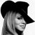 Pixelated grayscale image of a person wearing a black wide-brimmed hat, with light-colored hair visible beneath the brim, set against a plain white background.