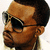 Pixelated close-up of a person's face wearing dark sunglasses with a light-colored frame, showing a side profile against a light background.