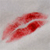 Red lips with a glossy texture on a light gray background, forming a kissing shape.