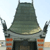 A pixelated image of a dark green, pointed roof structure with two vertical supports and orange brick-like sections below.