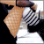 Pixelated close-up of a character with light brown hair, wearing a black and white checkered garment over a white top against dark background.
