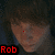 Pixelated image of a person's face with a red dot on the forehead, red text reading "Rob" in the bottom-left corner, and a dark background.