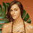 A pixelated image of a woman with long brown hair wearing a light-colored bikini top, standing against an orange background with green foliage.