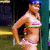Pixelated image of a person in a bikini top with a large circular object, set against a dark background with green and blue elements.