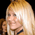 A static pixelated image shows a person with long blonde hair, light skin, and a black choker necklace against a dark background.