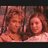 Two pixelated figures with reddish-brown hair and light skin tones sit side-by-side against a dark background, rendered in low-resolution digital art style.